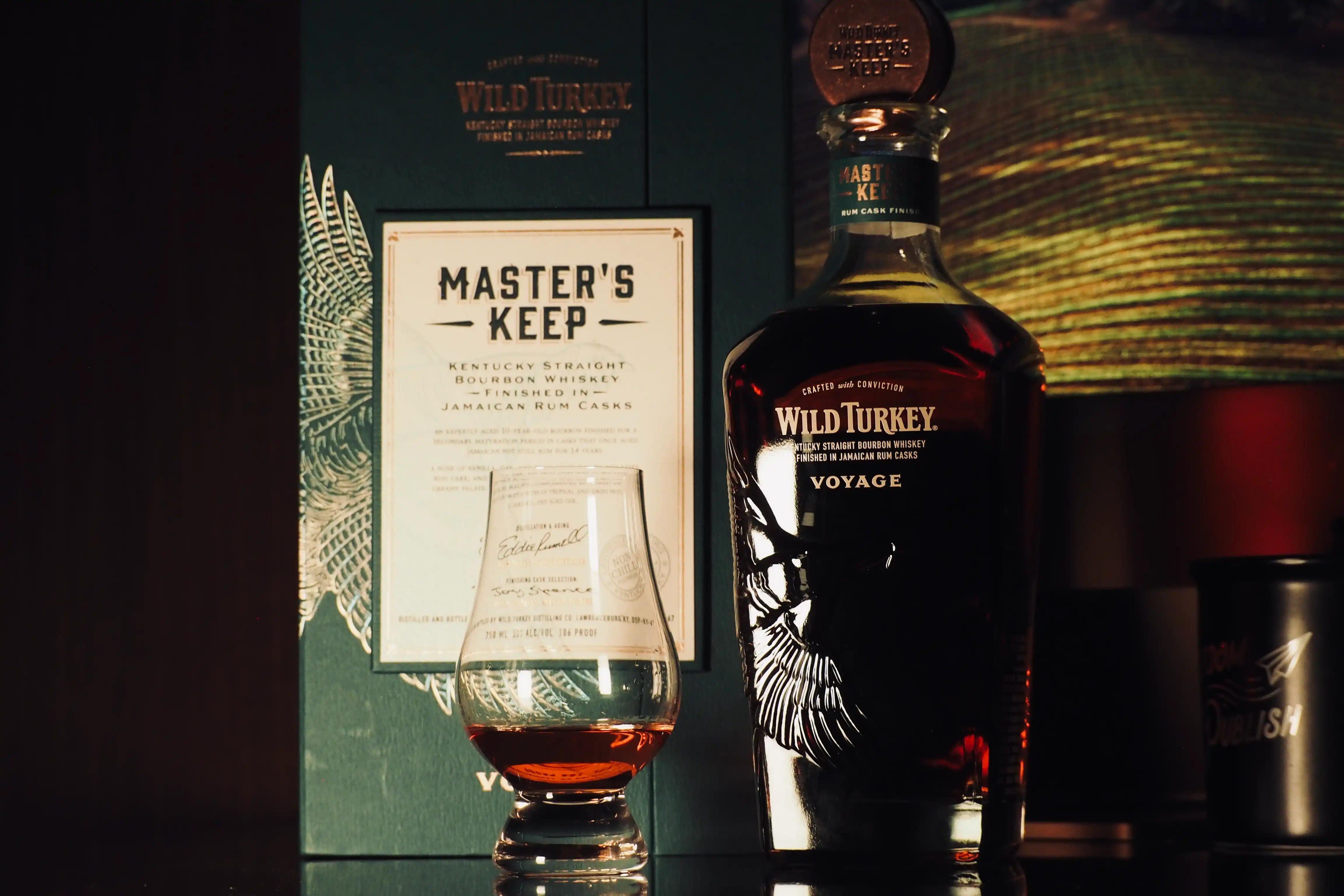 Opened Wild Turkey Master's Keep Voyage bottle next to glass with whiskey